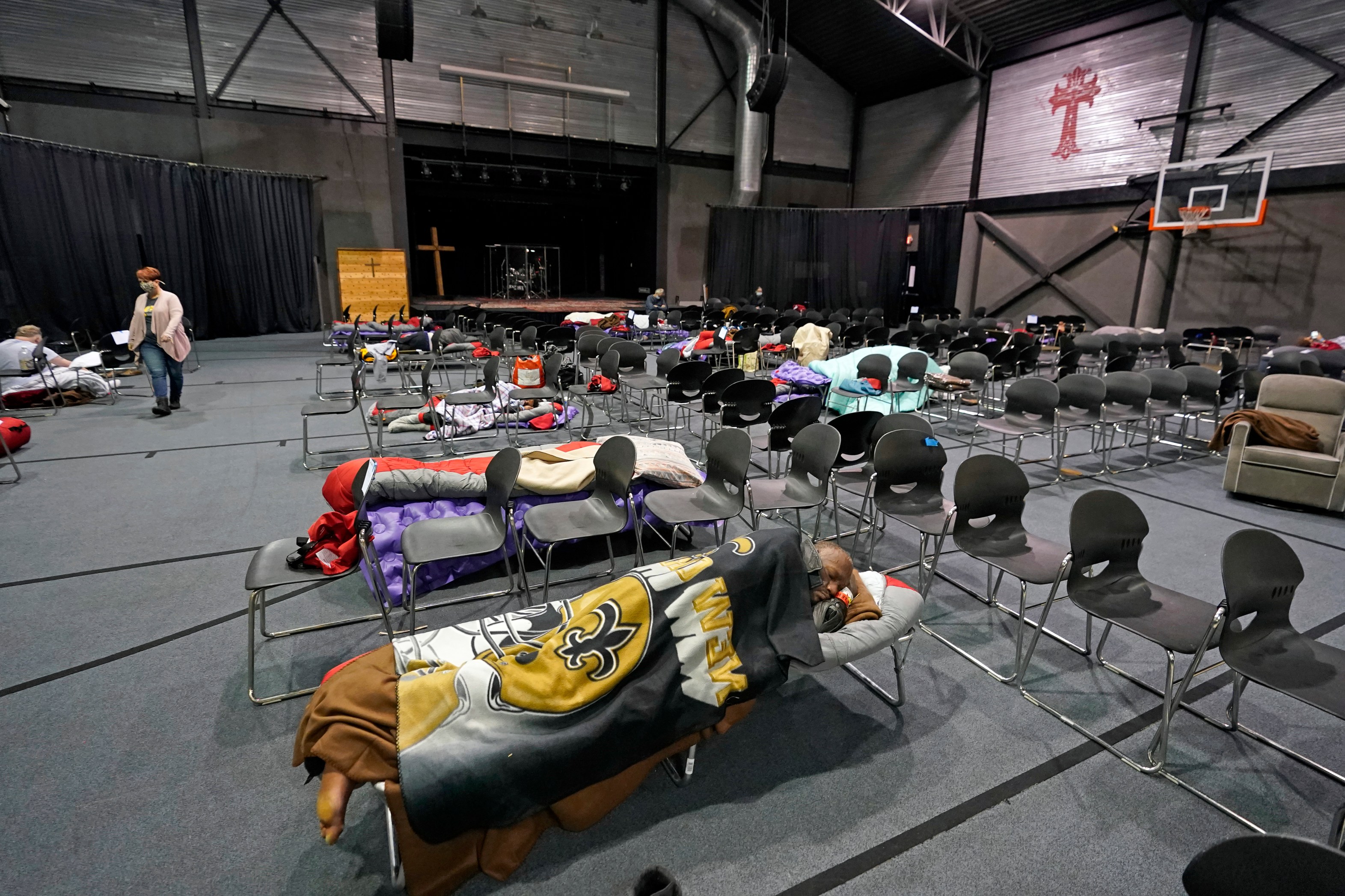 People seeking shelter from below freezing temperatures rest inside a church warming center Tuesday, Feb. 16, 2021, in Houston. More than 4 million people in Texas still had no power a full day after historic snowfall and single-digit temperatures created a surge of demand for electricity to warm up homes unaccustomed to such extreme lows, buckling the state's power grid and causing widespread blackouts. (AP Photo/David J. Phillip)