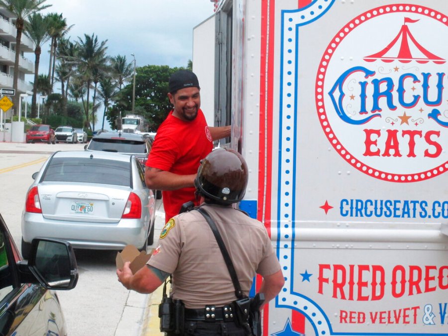 Robert Martinez talks with a law enforcement officer after handing him a hot meal from his food truck in Surfside, Fla., Tuesday, June 29, 2021. A small army of volunteers mobilized to deliver bottled water and energy drinks, chicken tenders and pizzas to law enforcement and emergency crews working long shifts after the deadly collapse of a condominium tower in the city, near Miami. (AP Photo/Russ Bynum)