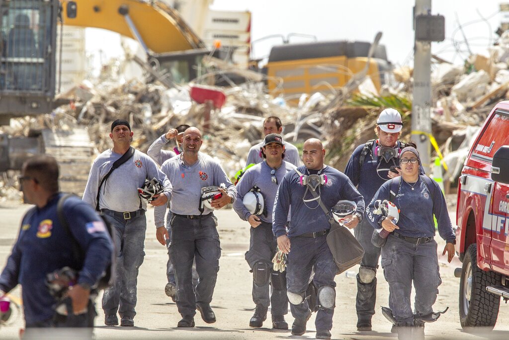 Rescuers walk away from the rubble of the Champlain Towers South collapse, during a shift change, in Surfside, Fla. on Thursday, July 8, 2021. Rescue workers now focused on finding remains instead of survivors in the rubble of the Florida condominium collapse vowed to keep up their search for victims until they cleared all the debris at the site. (Pedro Portal/Miami Herald via AP)