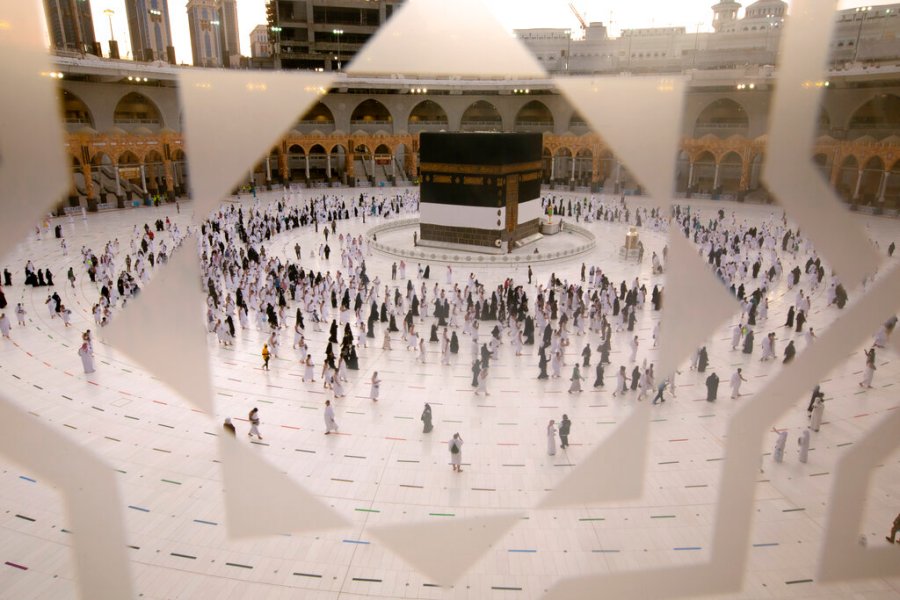 Muslim pilgrims are seen through a glass window as they circumambulate the Kaaba, the cubic building at the Grand Mosque, as they wear masks and keep to social distancing, a day before the annual hajj pilgrimage, Saturday, July 17, 2021. The pilgrimage to Mecca required once in a lifetime of every Muslim who can afford it and is physically able to make it, used to draw more than 2 million people. But for a second straight year it has been curtailed due to the coronavirus with only vaccinated people in Saudi Arabia able to participate. (AP Photo/Amr Nabil)