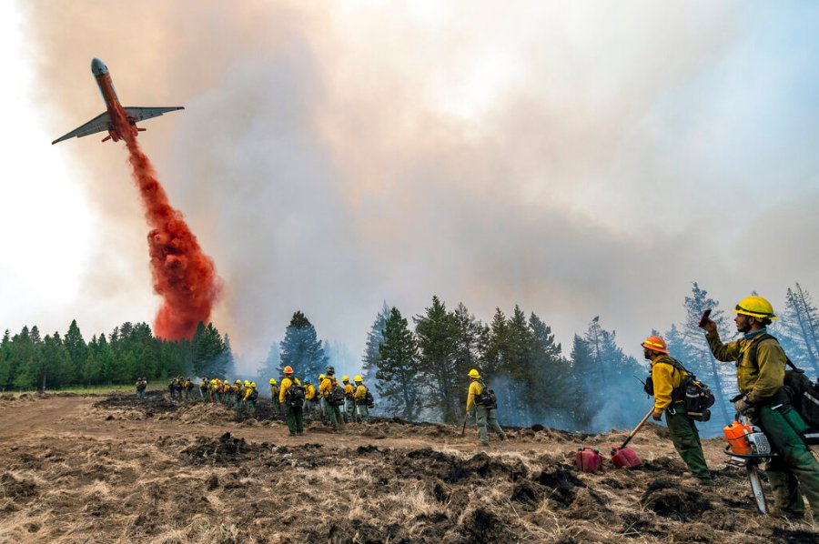 Wildland firefighters watch and take video with their cellphones as a plane drops fire retardant on Harlow Ridge above the Lick Creek Fire, southwest of Asotin, Wash., Monday, July 12, 2021. The fire, which started last Wednesday, has now burned over 50,000 acres of land between Asotin County and Garfield County in southeast Washington state. (Pete Caster/Lewiston Tribune via AP)