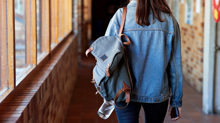 Young woman with backpack walking in corridor