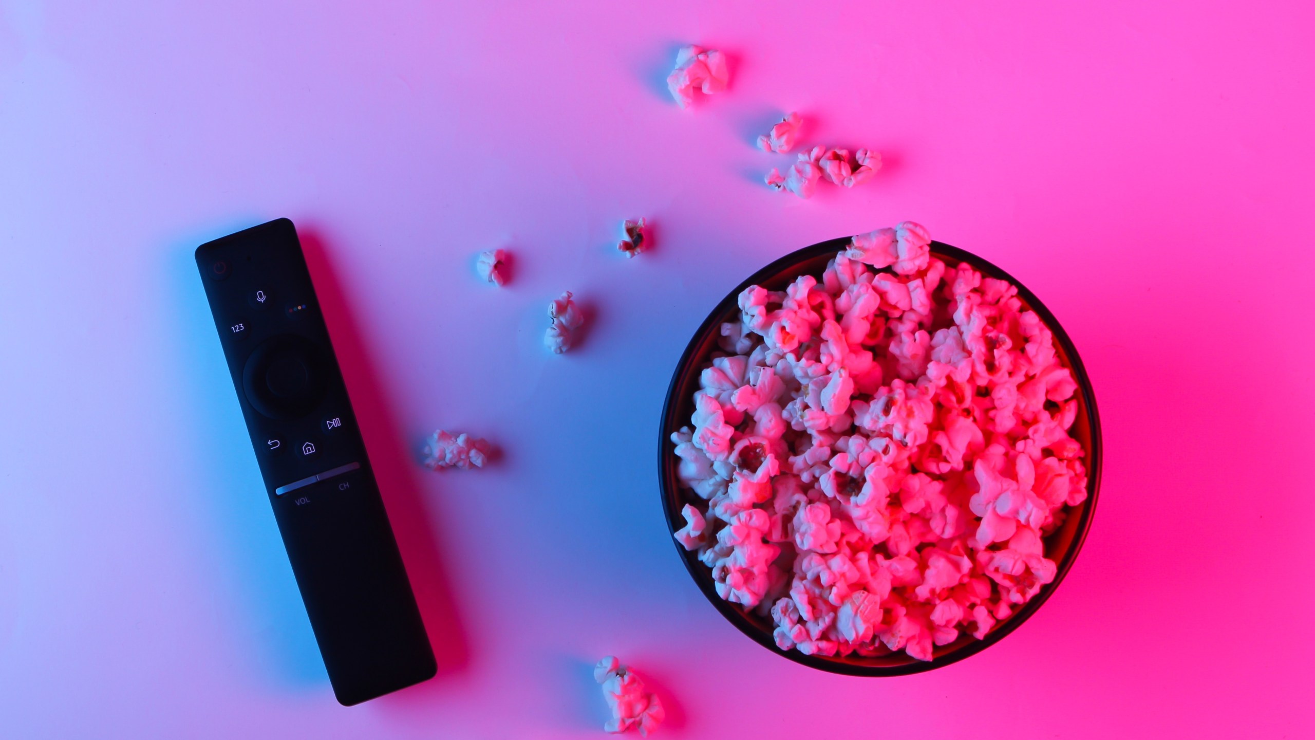 Tv remote and bowl of popcorn. Neon pink blue light. Leisure and entertainment concept (iStock/Getty Images)