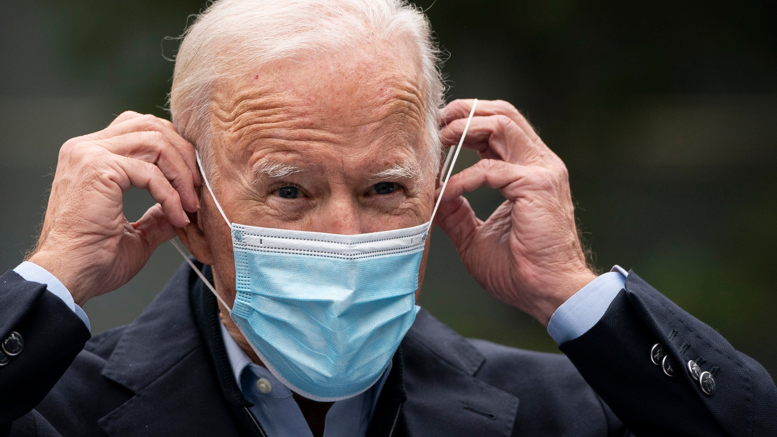 Joe Biden puts on a face mask while speaking to reporters at a voter mobilization center on October 26 in Chester, Pennsylvania. In Pennsylvania, (Photo by Drew Angerer/Getty Images)