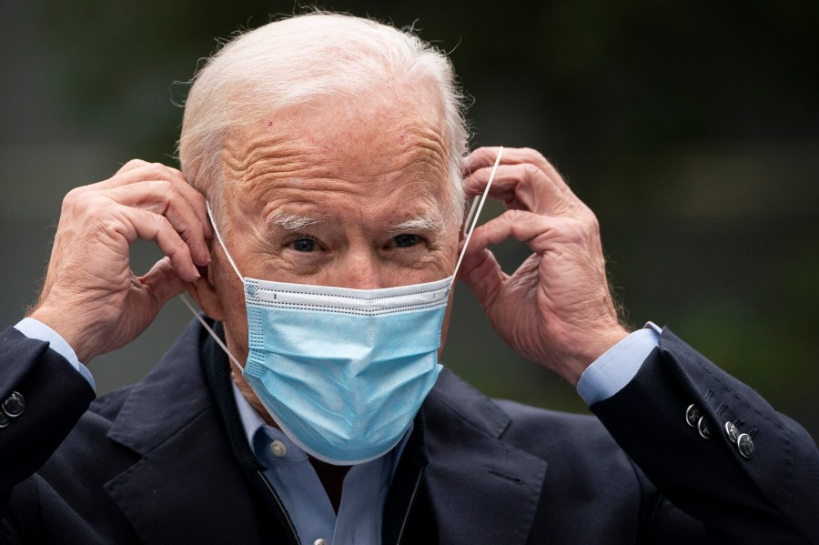 Joe Biden puts on a face mask while speaking to reporters at a voter mobilization center on October 26 in Chester, Pennsylvania. In Pennsylvania, (Photo by Drew Angerer/Getty Images)