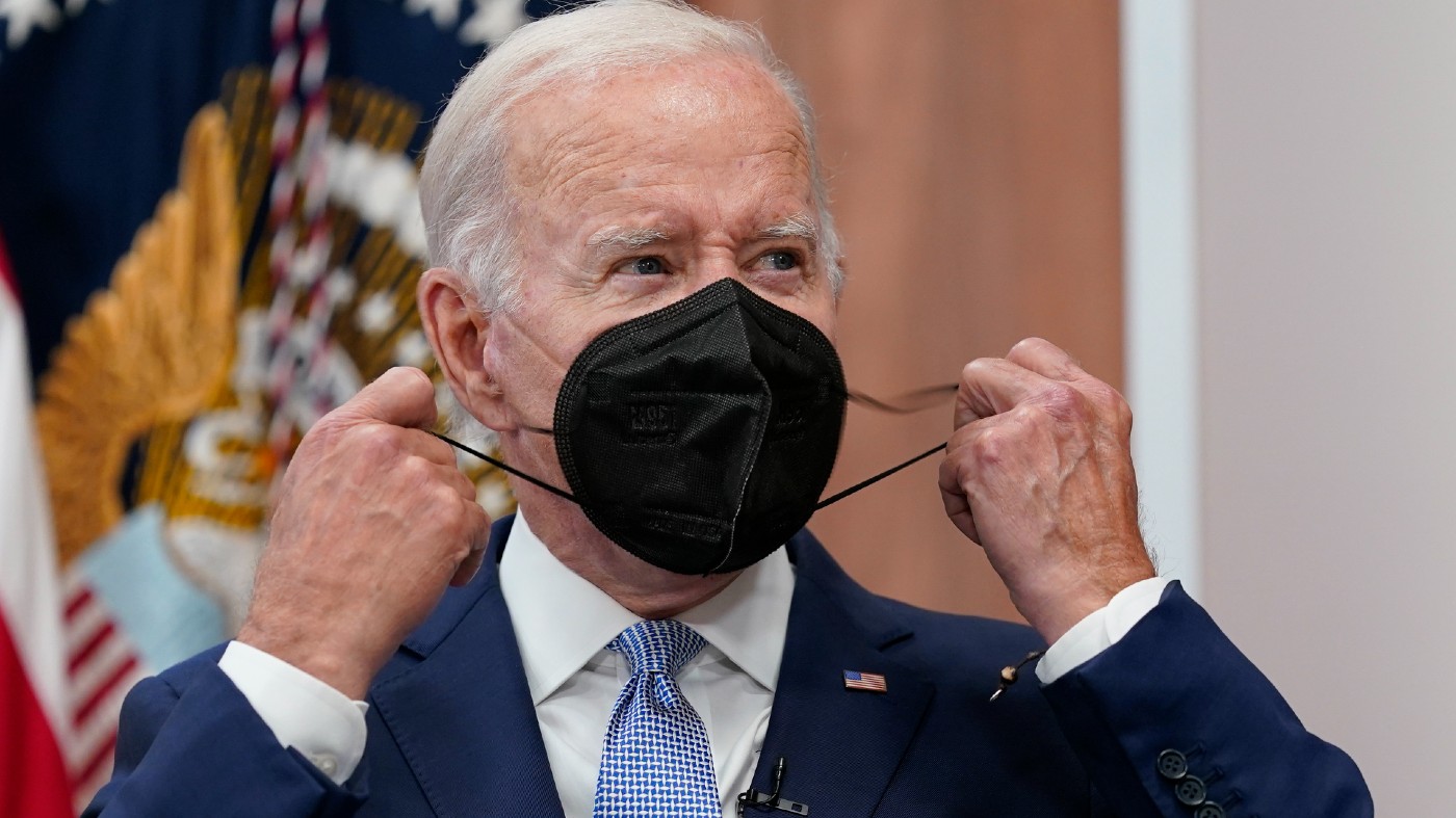 President Joe Biden removes his face mask before a 2022 speech.