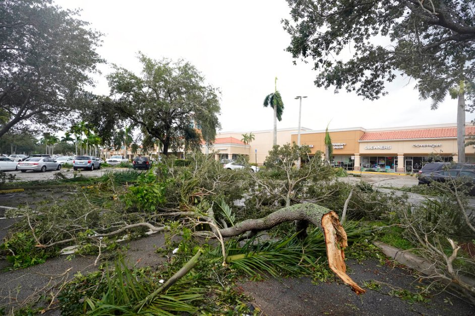 Tree limbs and palm fronds, knocked down from wind produced by the outer bands of Hurricane Ian, litter a parking lot of a shopping center, Wednesday, Sept. 28, 2022, in Cooper City, Fla. (AP Photo/Wilfredo Lee)