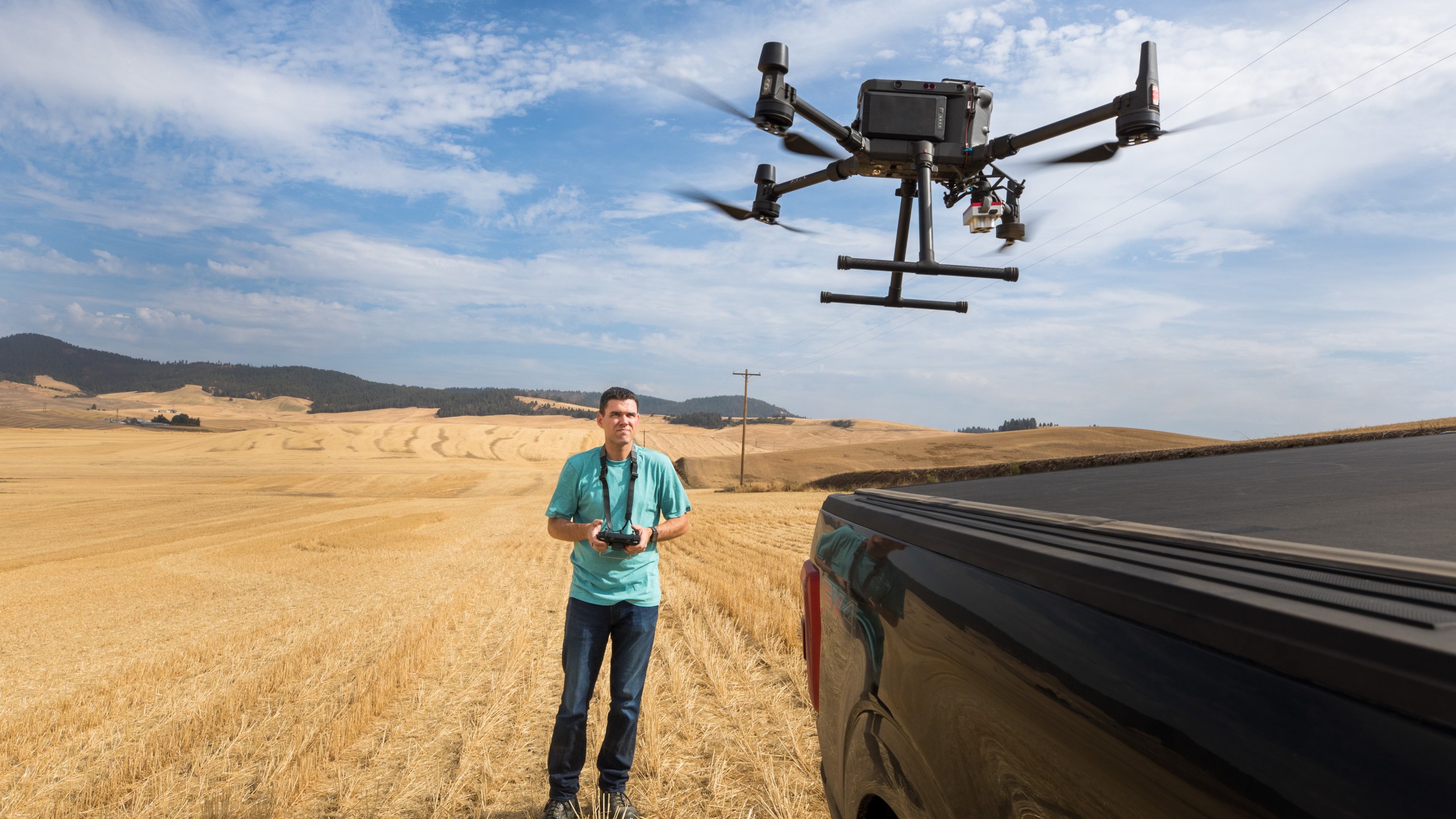 A man flies a drone over an empty farm field