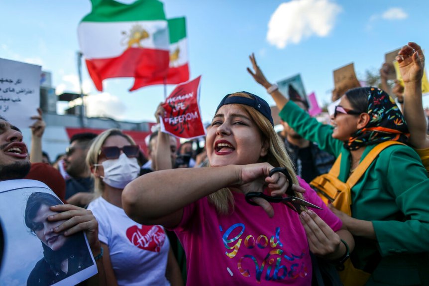 A woman cuts her hair during a protest against the death of Iranian Mahsa Amini, in Istanbul, Turkey, Sunday, Oct. 2, 2022. Thousands of Iranians have taken to the streets over the last two weeks to protest the death of Mahsa Amini, a 22-year-old woman who had been detained by Iran's morality police in the capital of Tehran for allegedly not adhering to Iran's strict Islamic dress code. (AP Photo/Emrah Gurel)