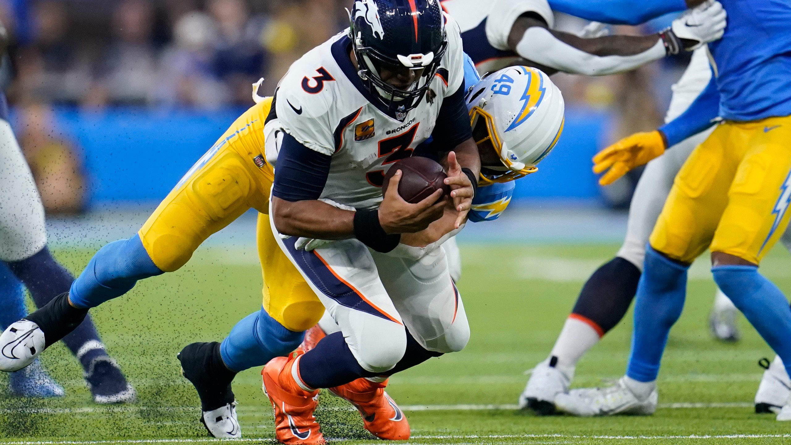 A football player holding a football on grass.