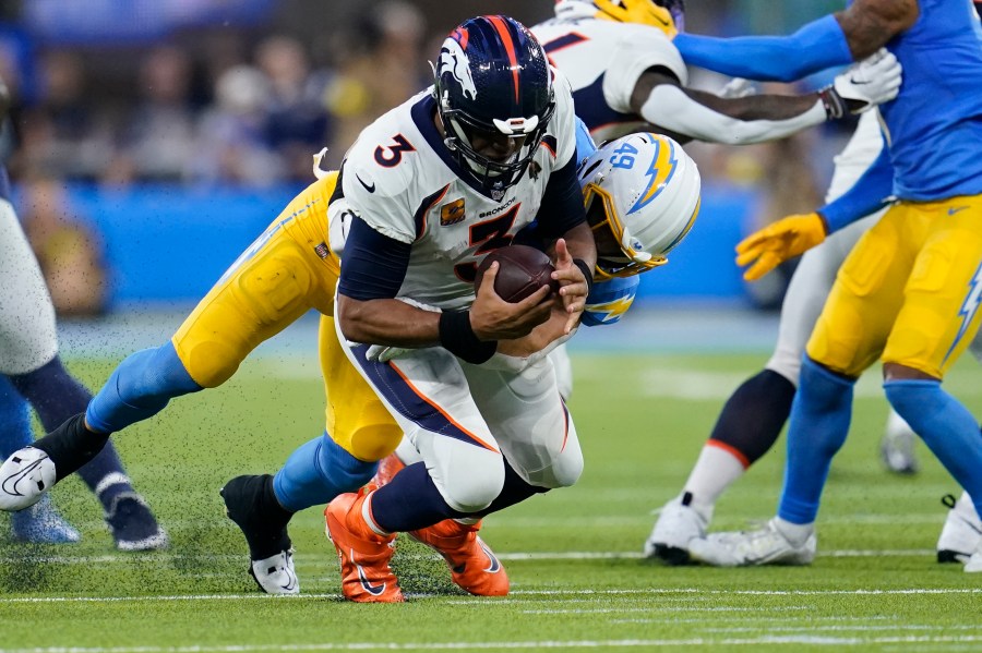 A football player holding a football on grass.