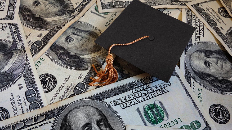 A graduation hat on top of a pile of money