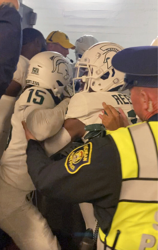 Security and police break up a scuffle between players from Michigan and Michigan State football teams in the Michigan Stadium tunnel after an NCAA college football game on Saturday, Oct. 29, 2022 in Ann Arbor, Mich. Michigan State President Samuel Stanley has apologized and says the actions of the football players who were involved in a postgame melee with Michigan players are “unacceptable.” He also says the players involved would be held responsible by coach Mel Tucker. (Kyle Austin/MLive Media Group via AP)