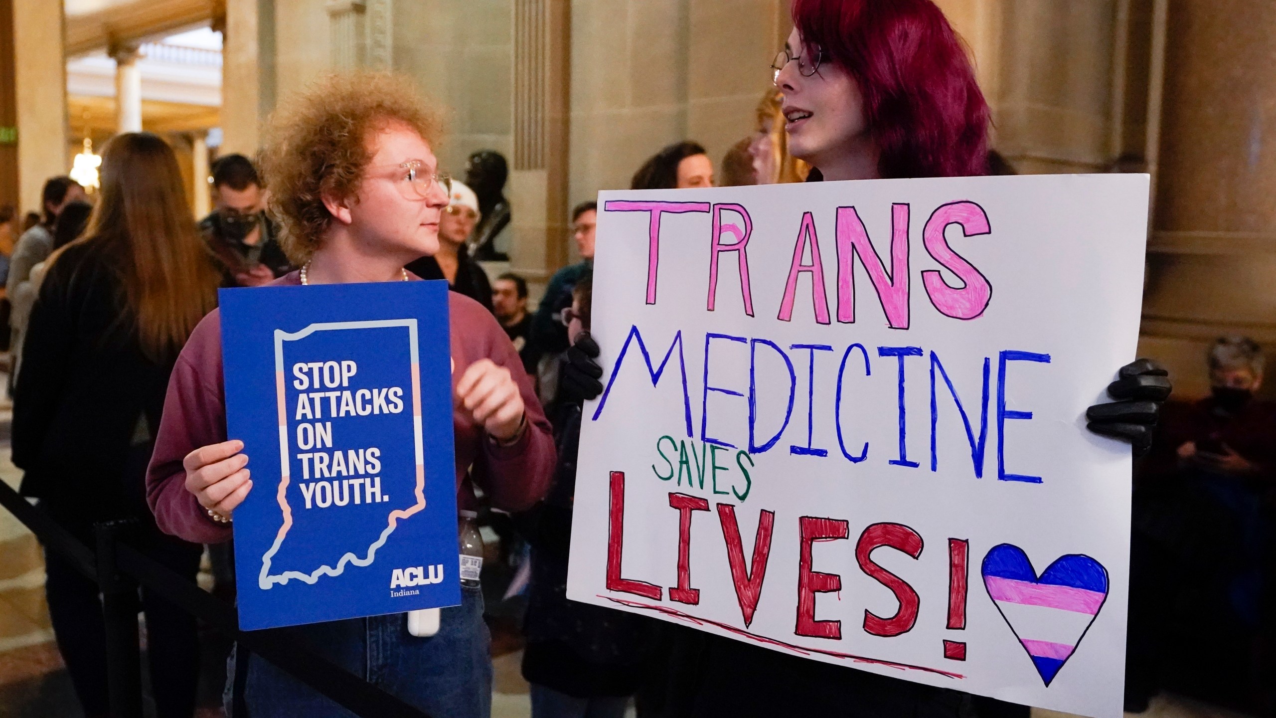 FILE - Protesters stand outside of the Senate chamber at the Indiana Statehouse on Feb. 22, 2023, in Indianapolis. Republican Governors in Indiana and Idaho have signed into law bills banning gender-affirming care for minors early April 2023, making those states the latest to prohibit transgender health care this year. (AP Photo/Darron Cummings, File)