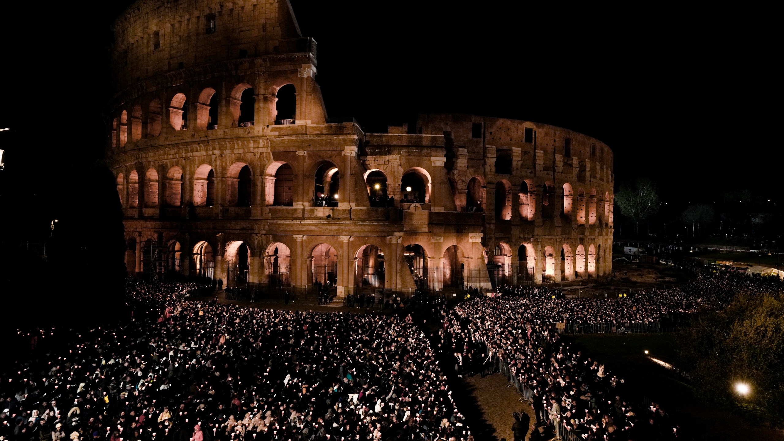 People hold candles during a Via Crucis (Way of the Cross) torchlight procession on Good Friday, in Rome, Friday, April 7, 2023. The Vatican says Pope Francis won't go to the Colosseum for the traditional Good Friday procession but instead he will watch it from his home at the Vatican due to unseasonably cold nighttime temperatures in Rome. (AP Photo/Alessandra Tarantino)