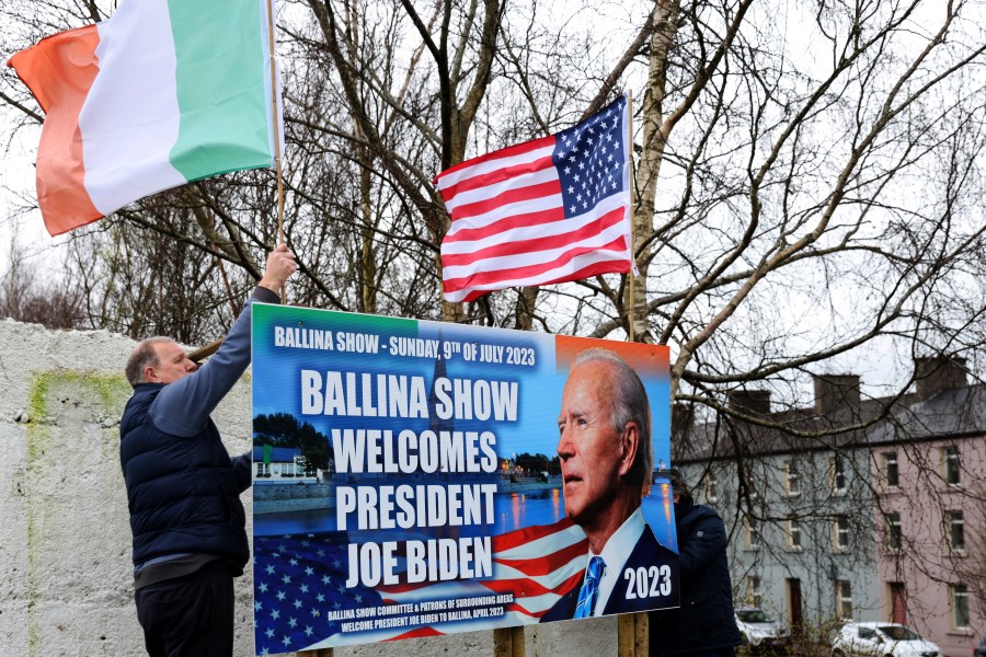 Ray Clarke, left, and Eddie Ruane put up flags in Ballina, Ireland, Tuesday, April, 4, 2023. Excitement is building in Ballina, a small Irish town that was home to some of President Joe Biden's ancestors. Biden is scheduled to visit the town next week, part of a four-day trip to Ireland and neighboring Northern Ireland. (AP Photo/Peter Morrison)