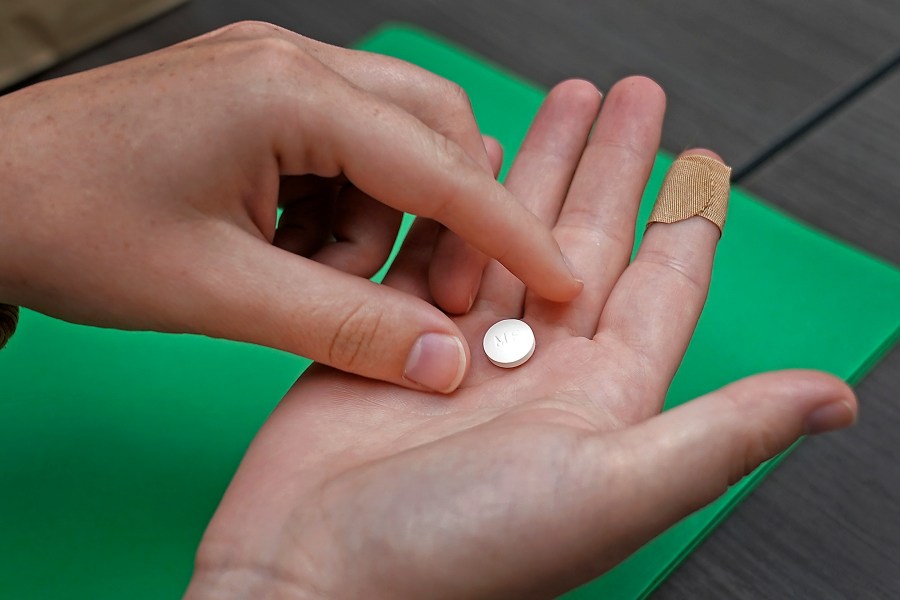 FILE - A patient prepares to take the first of two pills for a medication abortion during a visit to a clinic in Kansas City, Kan., on Wednesday, Oct. 12, 2022. Some abortion clinics are fielding lots of calls from patients since a Friday, April 7, 2023 court ruling threatened the availability of a main drug used in medication abortion, mifepristone. Patients are concerned about whether they can still get the care they need. (AP Photo/Charlie Riedel, File)