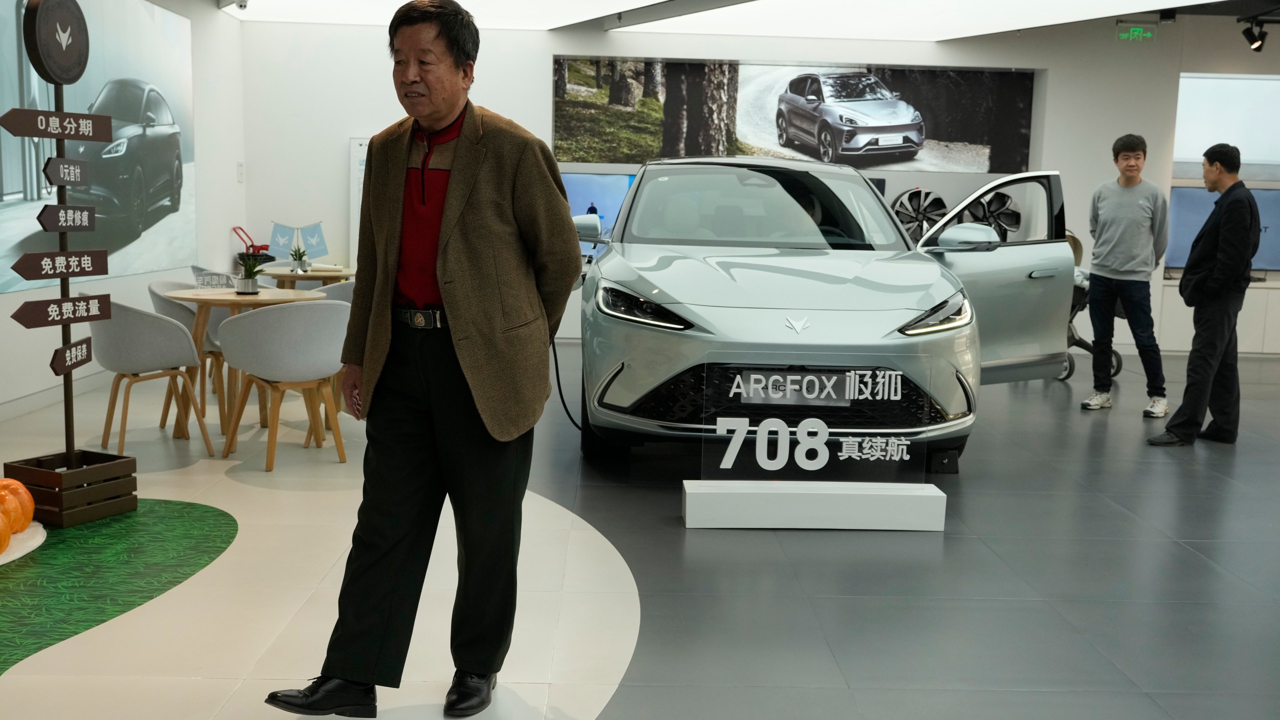 Visitors look at the Arcfox a-S, an all electric car from Chinese automaker BAIC which claims to have a 708km range on a single charge, at a show room in Beijing, Thursday, April 13, 2023. Global and Chinese automakers plan to unveil more than a dozen new electric SUVs, sedans and muscle cars this week at the Shanghai auto show, their first full-scale sales event in four years in a market that has become a workshop for developing electrics, self-driving cars and other technology. (AP Photo/Ng Han Guan)