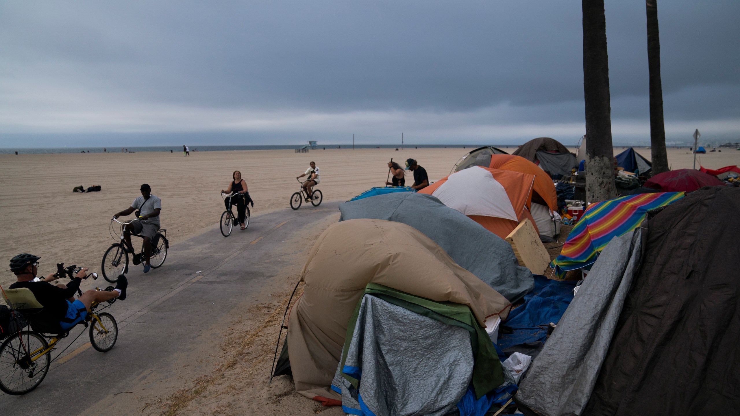 FILE - People ride their bikes past a homeless encampment set up along the boardwalk in the Venice neighborhood of Los Angeles on June 29, 2021. Democratic Mayor Karen Bass, who was elected in November 2023 after promising to take on the city’s out-of-control homeless crisis, announced Monday, April 17, she would recommend spending what she called a record $1.3 billion next year to get unhoused people into shelter and treatment programs. (AP Photo/Jae C. Hong, File)