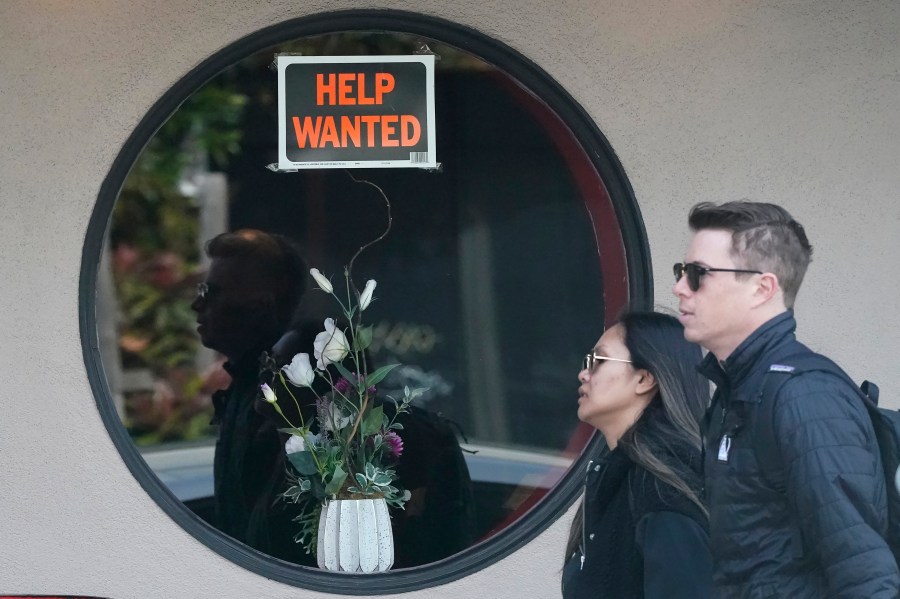 Pedestrians walk past a help wanted sign posted on the door of a restaurant in San Francisco, Tuesday, April 18, 2023. On Thursday, the Labor Department reports on the number of people who applied for unemployment benefits last week. (AP Photo/Jeff Chiu)