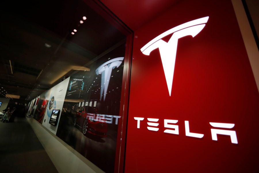 FILE - A sign bearing the Tesla company logo is displayed outside a Tesla store in Cherry Creek Mall in Denver, Colorado, Feb. 9, 2019. Tesla's first-quarter vehicle sales in 2023 rose 36% after the company cut prices twice in a bid to stimulate demand. (AP Photo/David Zalubowski, File)