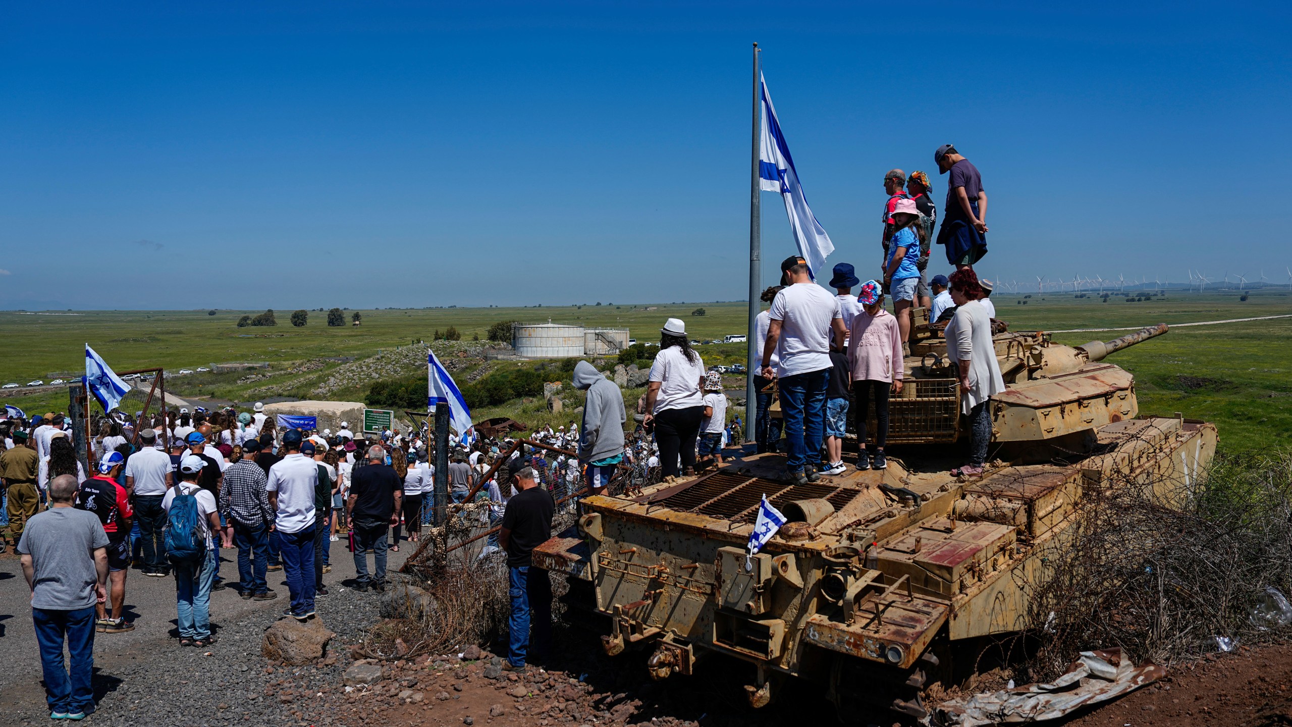 Israelis stand still to observe two minutes of silence as air raid sirens sound to mark Israel's annual Memorial Day for fallen soldiers, in Tel Saki memorial site for 1973's Mideast war in the Israeli-controlled Golan Heights, on the border with Syria, Tuesday, April 25, 2023. (AP Photo/Ariel Schalit)