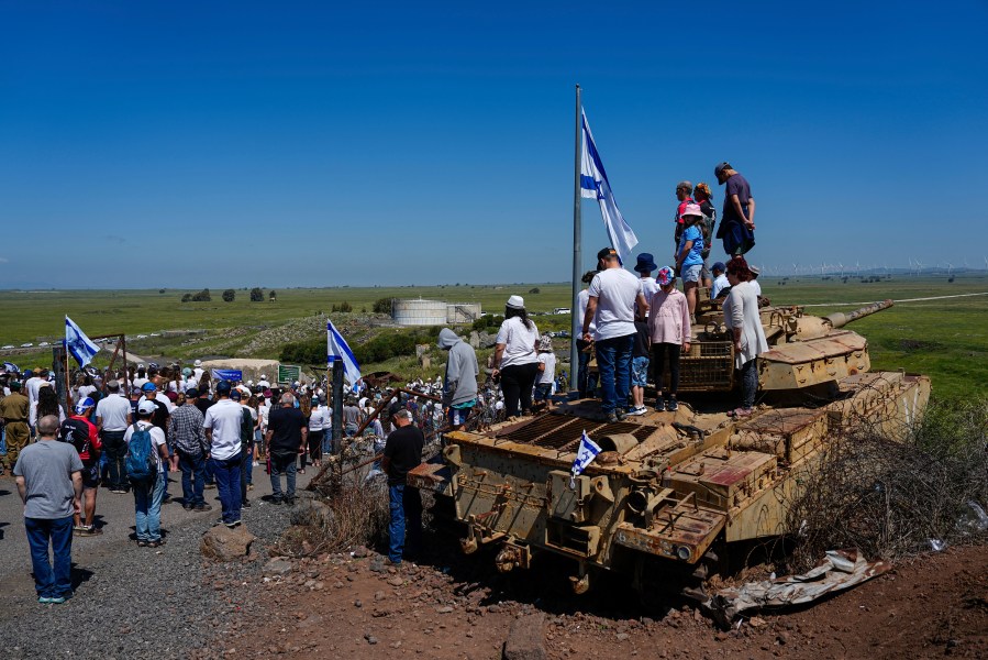 Israelis stand still to observe two minutes of silence as air raid sirens sound to mark Israel's annual Memorial Day for fallen soldiers, in Tel Saki memorial site for 1973's Mideast war in the Israeli-controlled Golan Heights, on the border with Syria, Tuesday, April 25, 2023. (AP Photo/Ariel Schalit)