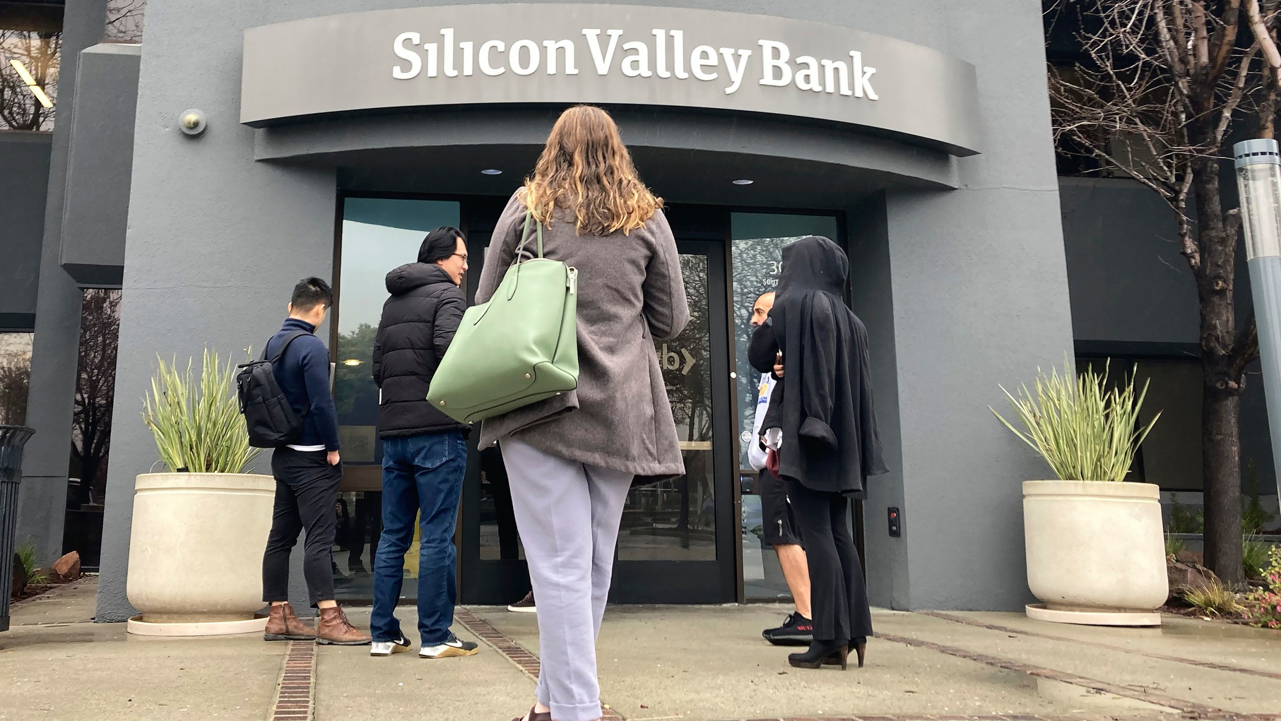 File - People stand outside a Silicon Valley Bank branch in Santa Clara, Calif., Friday, March 10, 2023. The Federal Reserve is scheduled Friday to release a highly-anticipated review of its supervision of Silicon Valley Bank, the go-to bank for venture capital firms and technology start-ups that failed spectacularly in March. (AP Photo/Jeff Chiu, File)