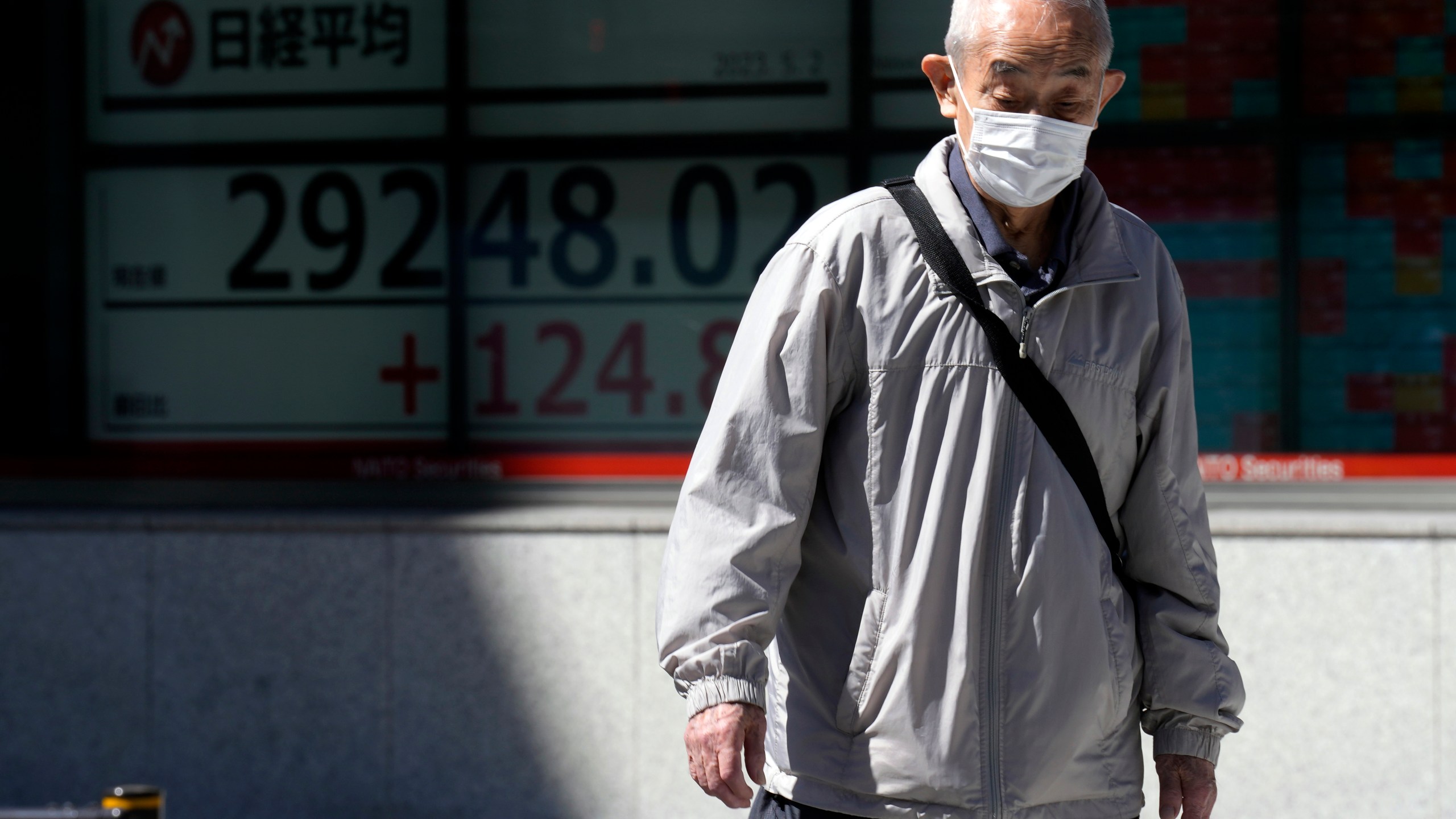 A person walks past an electronic stock board showing Japan's Nikkei 225 index at a securities firm Tuesday, May 2, 2023, in Tokyo. Asian shares were mixed Tuesday with some markets closed or anticipating holidays and investors showing muted reaction to the latest historic U.S. banking failure. (AP Photo/Eugene Hoshiko)