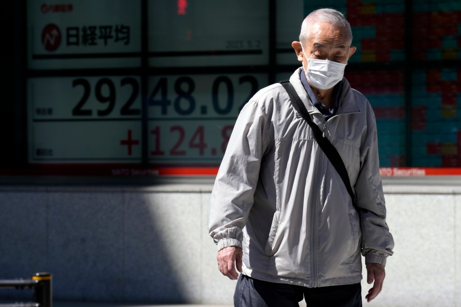 A person walks past an electronic stock board showing Japan's Nikkei 225 index at a securities firm Tuesday, May 2, 2023, in Tokyo. Asian shares were mixed Tuesday with some markets closed or anticipating holidays and investors showing muted reaction to the latest historic U.S. banking failure. (AP Photo/Eugene Hoshiko)