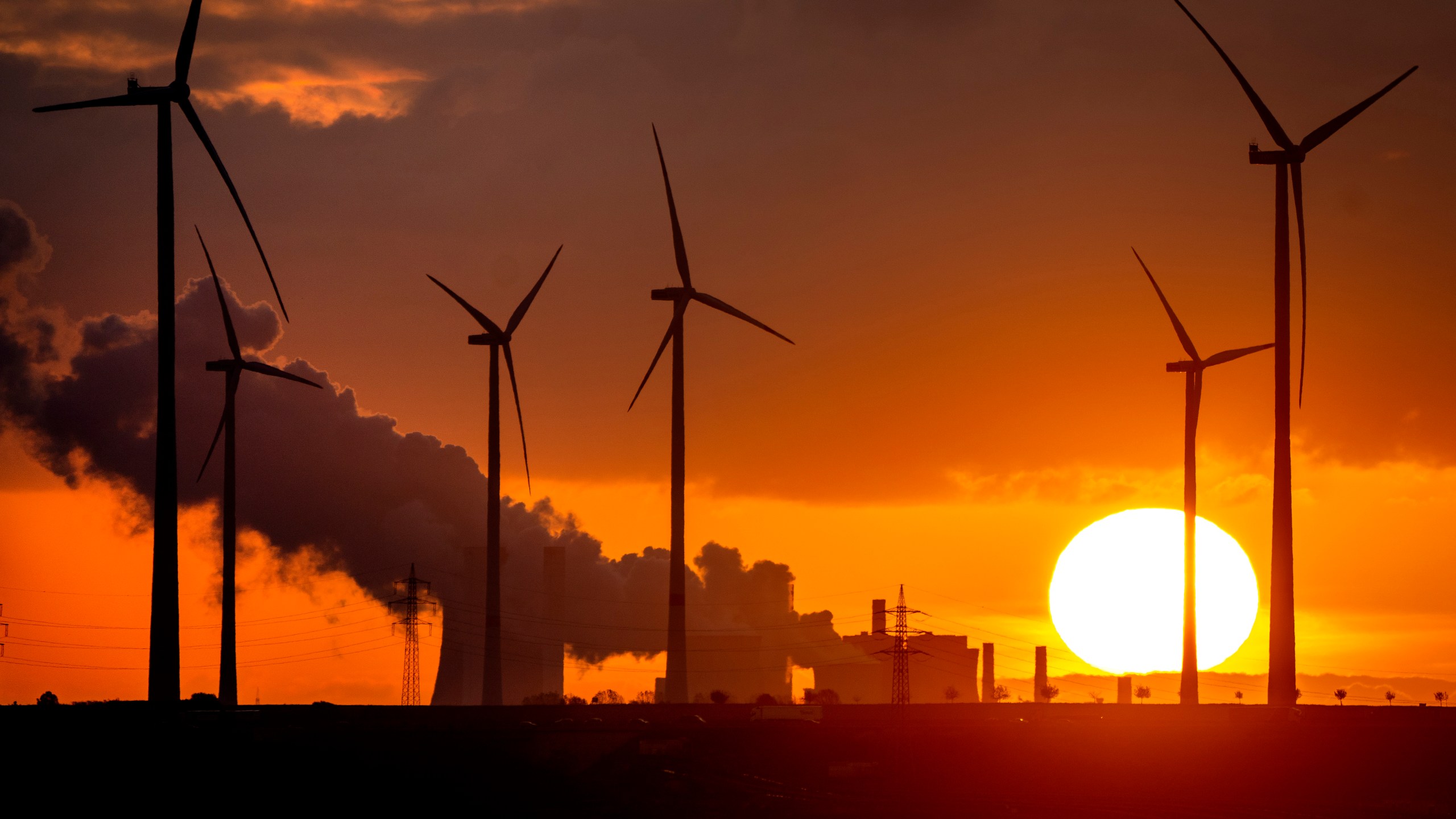 FILE - Steam rises from the coal-fired power plant near wind turbines Niederaussem, Germany, as the sun rises on Wednesday, Nov. 2, 2022. Germany has called for governments around the world to work on setting an ambitious target for renewable energy that would “ring in the end of the fossil fuel age” and help prevent dangerous global warming. (AP Photo/Michael Probst, File)