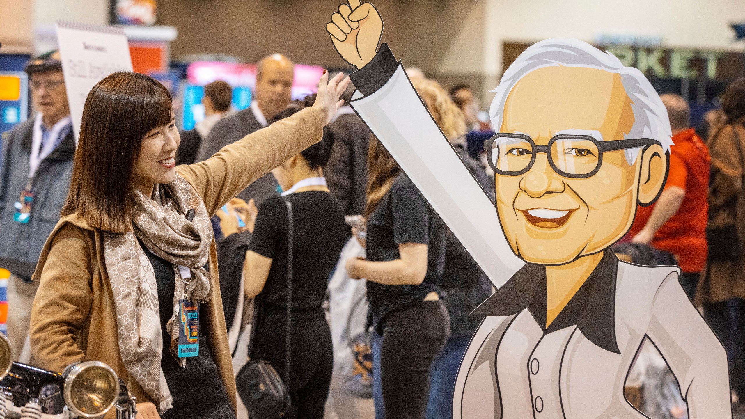 Hami Liu from Taiwan poses for a photo with a cardboard cutout of Warren Buffett at the See's Candies booth during the Berkshire Bazaar of Bargains at the CHI Health Center on Friday, May 5, 2023. (Chris Machian/Omaha World-Herald via AP)