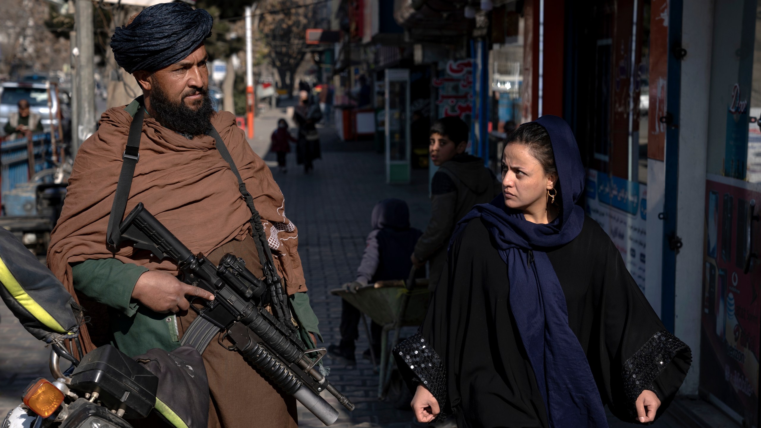 FILE - A Taliban fighter stands guard as a woman walks past in Kabul, Afghanistan, on Dec. 26, 2022. The United Nations' human rights chief on Tuesday Dec. 27, 2022. A U.N. report on Monday, May 8, 2023 condemned the Taliban for their harsh rule since seizing power in Afghanistan — including public execution, lashings, and amputations — and for ignoring international calls to respect human rights and freedoms. (AP Photo/Ebrahim Noroozi, File)