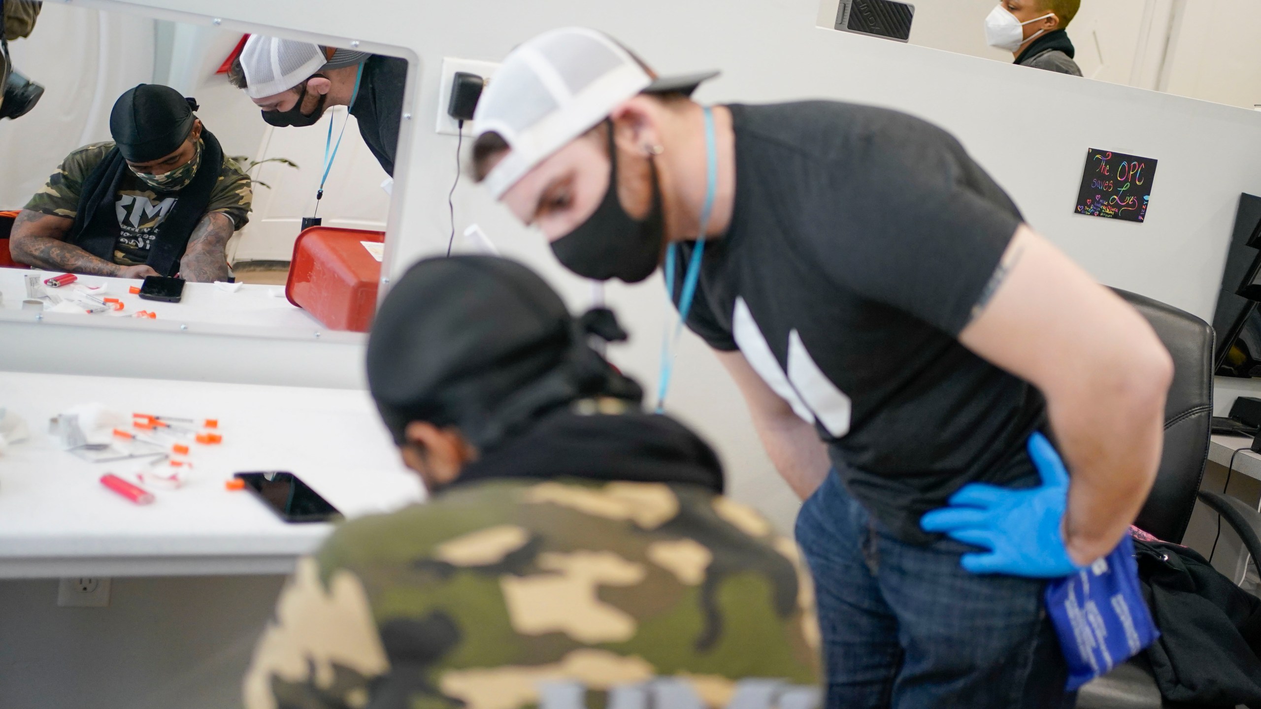 FILE - Brian Hackel, right, an overdose prevention specialist, helps Steven Baez, a client suffering addiction, find a vein to inject intravenous drugs at an overdose prevention center, OnPoint NYC, in New York, Feb. 18, 2022. For the first time, the U.S. government will pay for a large study measuring whether overdoses can be prevented by safe injection sites, places where people can use heroin and other narcotics and be revived if they take too much. The grant is expected to provide more than $5 million over four years to New York University and Brown University to study overdose prevention centers in New York City and Providence, R.I. (AP Photo/Seth Wenig, File)