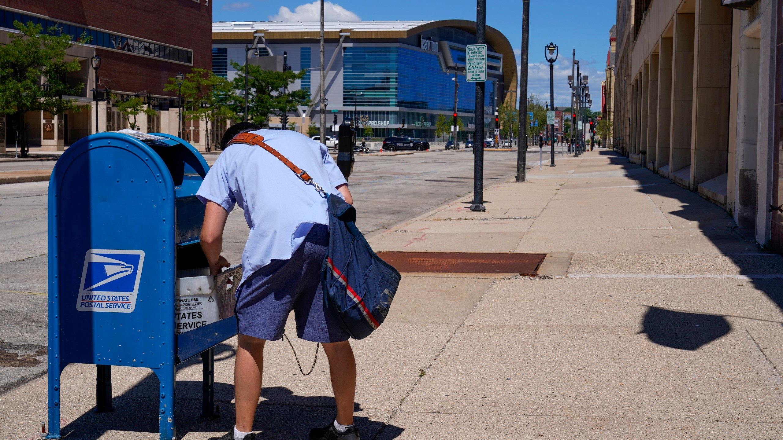 FILE - A postal worker empties a box near the Fiserv Forum on Aug. 18, 2020, in Milwaukee. Postal carriers have more worries than snow, rain or the gloom of night keeping them from their appointed rounds. These days, they're increasingly being robbed, often at gunpoint, from Maine to California. (AP Photo/Morry Gash, File)