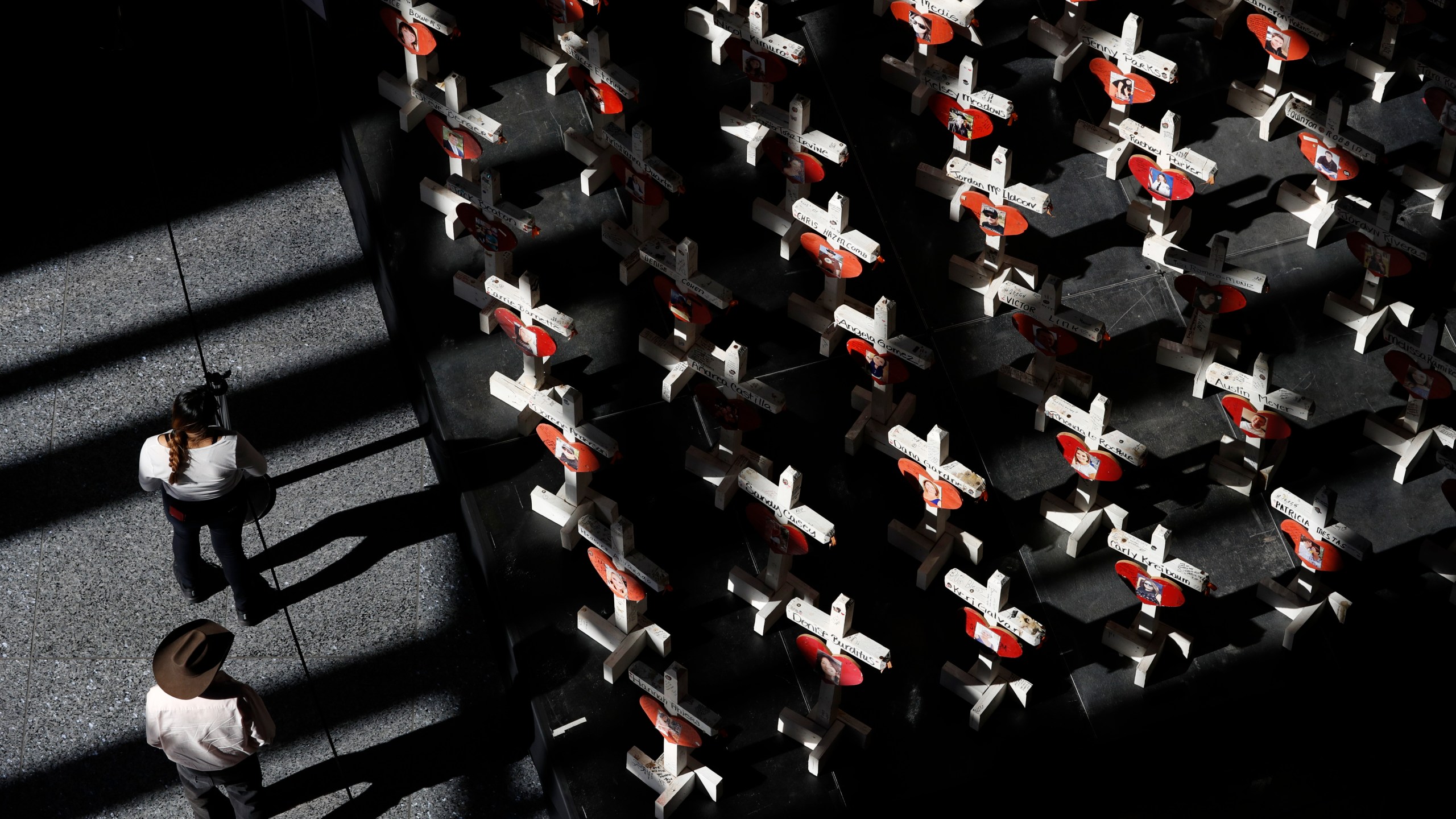 FILE - In this Sept. 25, 2018, photo, people look at a display of wooden crosses and a Star of David on display at the Clark County Government Center in Las Vegas. It was the deadliest mass shooting in modern U.S. history on the Las Vegas Strip in 2017. More than 100 people have been killed in mass shootings thus far in 2023, an average of one mass killing a week. (AP Photo/John Locher, File)