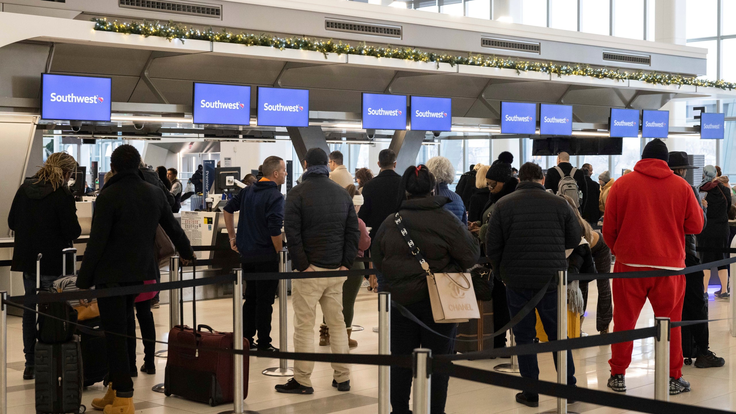 FILE - Passengers wait in line to check in for their flights at Southwest Airlines service desk at LaGuardia Airport, on Dec. 27, 2022, in New York. The Biden administration is working on new regulations that would require airlines to compensate passengers and cover their meals and hotel rooms if they are stranded for reasons within the airline's control. The White House said President Joe Biden and Transportation Secretary Pete Buttigieg would announce the start of the rulemaking process Monday May 8, 2023. (AP Photo/Yuki Iwamura, File)