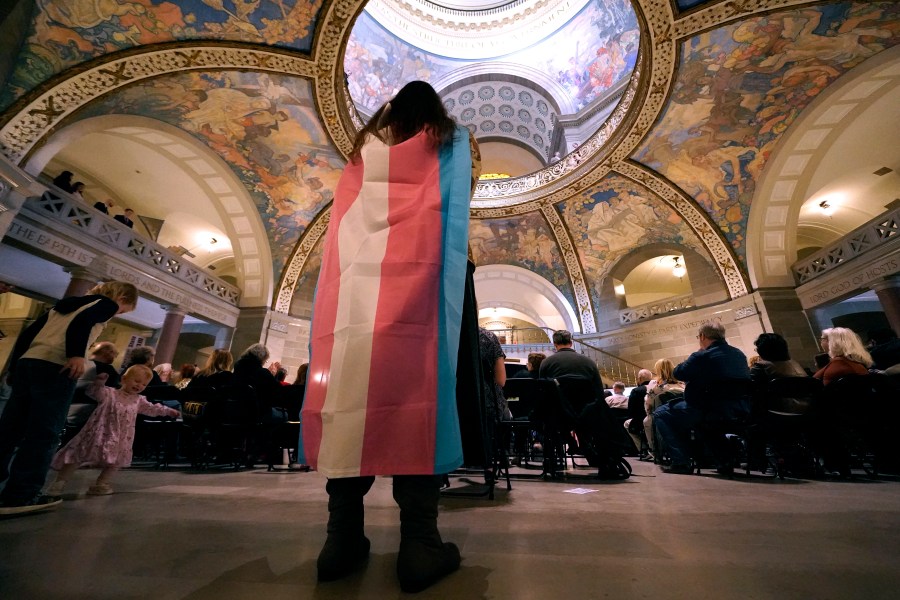 FILE - Glenda Starke wears a transgender flag as a counter protest during a rally in favor of a ban on gender-affirming health care legislation, March 20, 2023, at the Missouri Statehouse in Jefferson City, Mo. (AP Photo/Charlie Riedel, File)