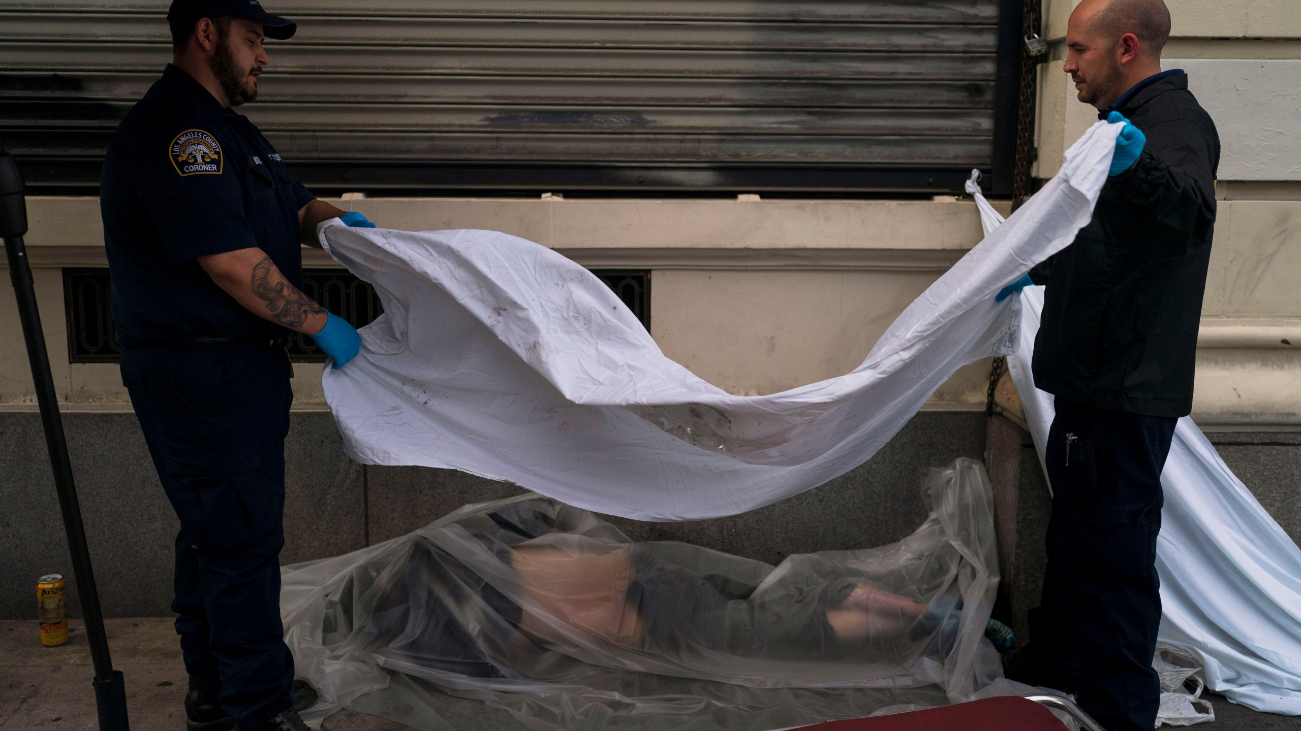 FILE - Forensic assistant Laurentiu Bigu, left, and investigator Ryan Parraz from the Los Angeles County coroner's office cover the body of a homeless man found dead on a sidewalk in Los Angeles on April 18, 2022. The 60-year-old man died from the effects of methamphetamine, according to his autopsy report. Drug overdose deaths in the U.S. went up slightly in 2022 after two big leaps during the pandemic. (AP Photo/Jae C. Hong, File)