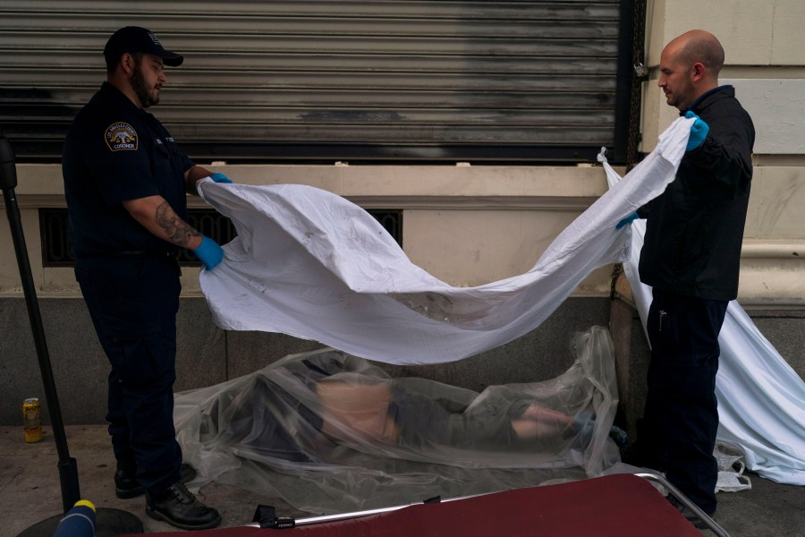 FILE - Forensic assistant Laurentiu Bigu, left, and investigator Ryan Parraz from the Los Angeles County coroner's office cover the body of a homeless man found dead on a sidewalk in Los Angeles on April 18, 2022. The 60-year-old man died from the effects of methamphetamine, according to his autopsy report. Drug overdose deaths in the U.S. went up slightly in 2022 after two big leaps during the pandemic. (AP Photo/Jae C. Hong, File)