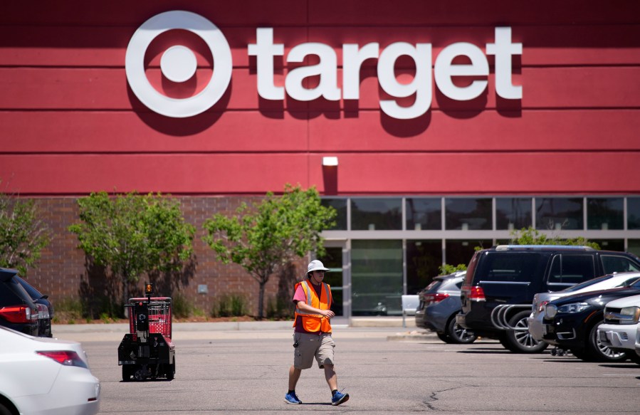 FILE - A worker collects shopping carts in the parking lot of a Target store on June 9, 2021, in Highlands Ranch, Colo. Target is removing certain items from its stores and making other changes to its LGBTQ merchandise nationwide ahead of Pride month, after an intense backlash from some customers including violent confrontations with its workers. (AP Photo/David Zalubowski, File)