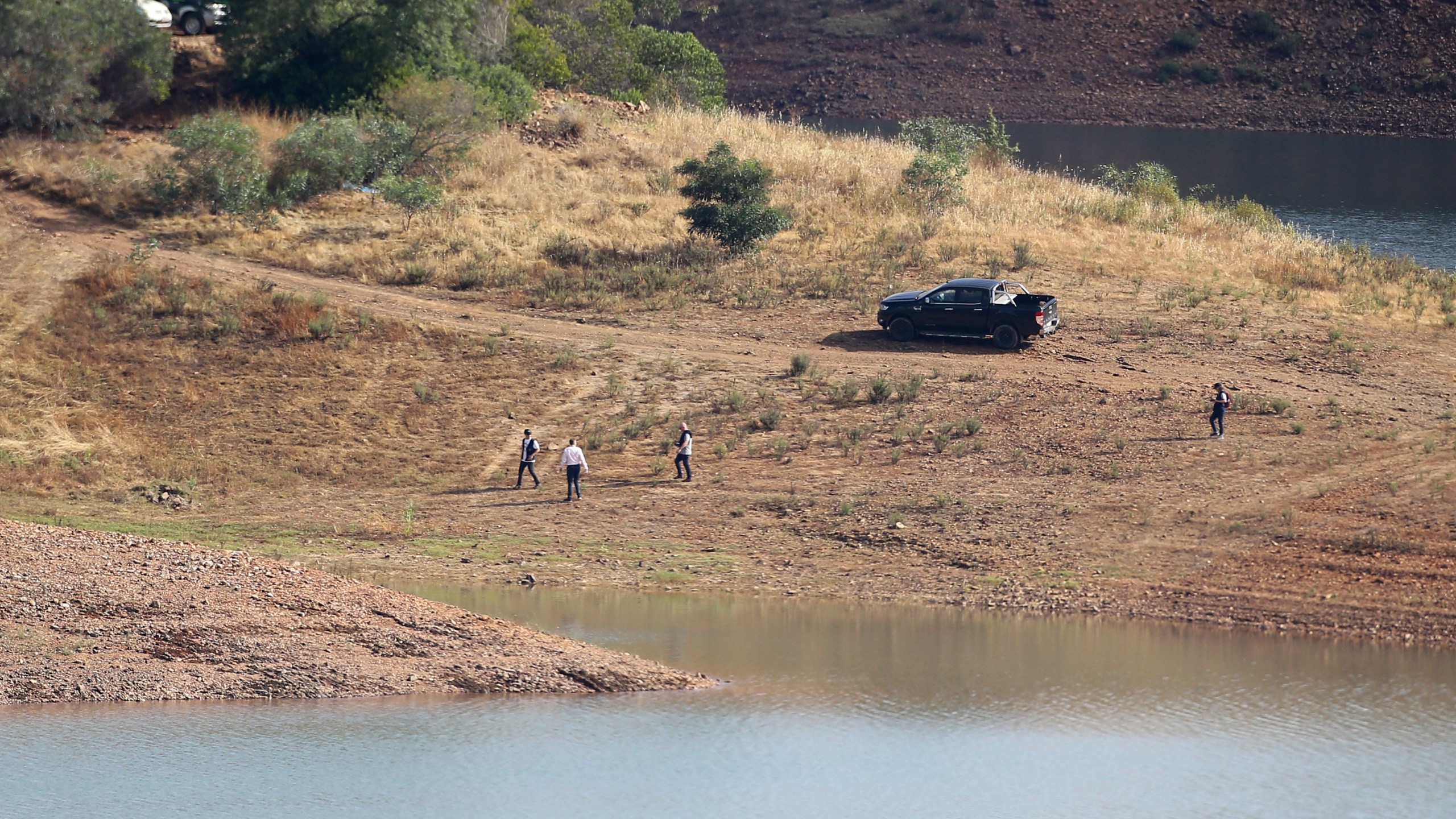 A police search team walk on the shore of the Arade dam near Silves, Portugal, Wednesday May 24, 2023. Portuguese police aided by German and British officers have resumed their search for Madeleine McCann, the British child who disappeared in the country's southern Algarve region 16 years ago. Some 30 officers could be seen in the area by the Arade dam, about 50 kilometers (30 miles) from Praia da Luz, where the 3-year-old was last seen alive in 2007. (AP Photo/Joao Matos)