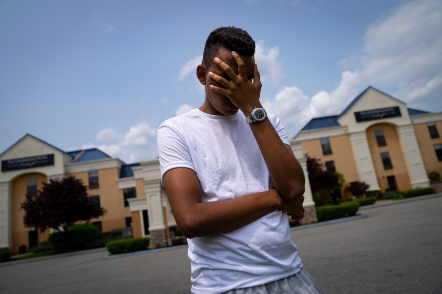 Mohamed, a 19-year-old fleeing political persecution in the northwest African country of Mauritania, poses for a photo that obscures his face to protect his identity, outside the Crossroads Hotel, before heading into town for a work opportunity, Monday, May 22, 2023, in Newburgh, N.Y. Mohamed is one of about 400 international migrants the city has been putting up in a small number of hotels in other parts of the state this month to relieve pressure on its overtaxed homeless shelter system. (AP Photo/John Minchillo)