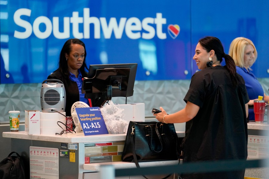 A Southwest airlines customer service representative, left, assists a traveler at the ticketing counter at Love Field airport, Friday, May 19, 2023, in Dallas. The unofficial start of the summer travel season is here, with airlines hoping to avoid the chaos of last year and travelers scrounging for ways to save a few bucks on pricey airfares and hotel rooms.(AP Photo/Tony Gutierrez)