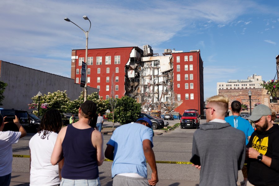 CORRECTS TO MAIN STREET INSTEAD OF WEST THIRD STREET-- Onlookers watch as emergency crews work the scene of a partial building collapse on the 300 block of Main Street, Sunday, May 28, 2023, in Davenport, Iowa. (Nikos Frazier/Quad City Times via AP)