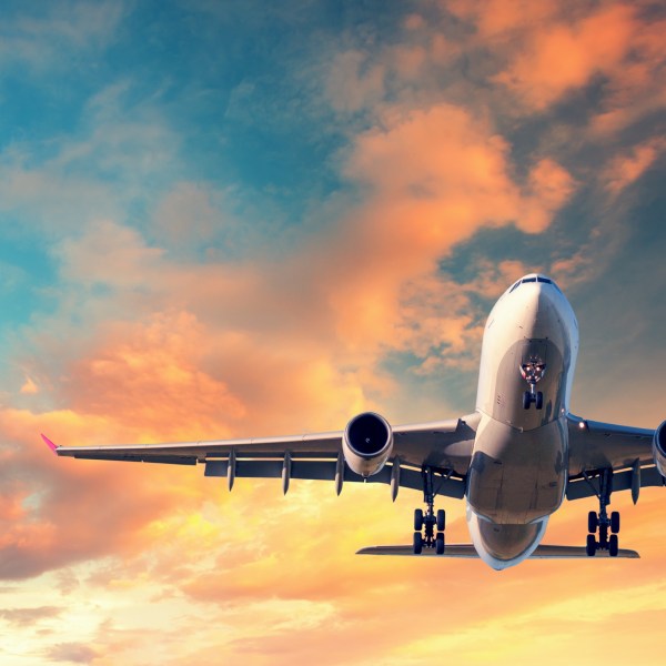 Landing airplane. Landscape with white passenger airplane is flying in the blue sky with multicolored clouds at sunset. Travel background. Passenger airliner. Business trip. Commercial aircraft - stock photo