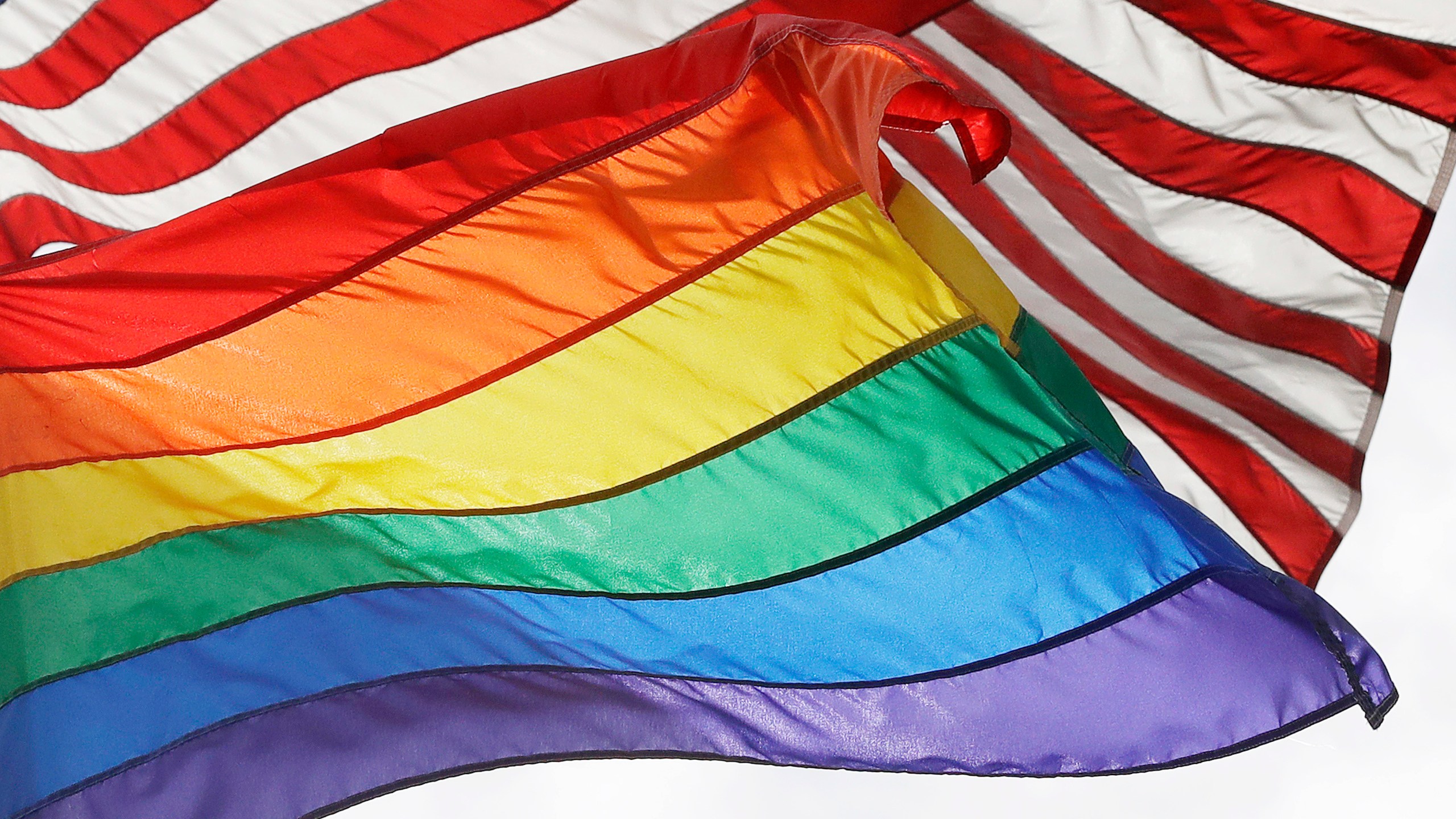 FILE - The LGBTQ+ pride flag flies beneath the American flag at the Stonewall National Monument, Oct. 11, 2017, in New York. (AP Photo/Mark Lennihan, File)