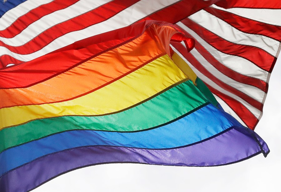 FILE - The LGBTQ+ pride flag flies beneath the American flag at the Stonewall National Monument, Oct. 11, 2017, in New York. (AP Photo/Mark Lennihan, File)