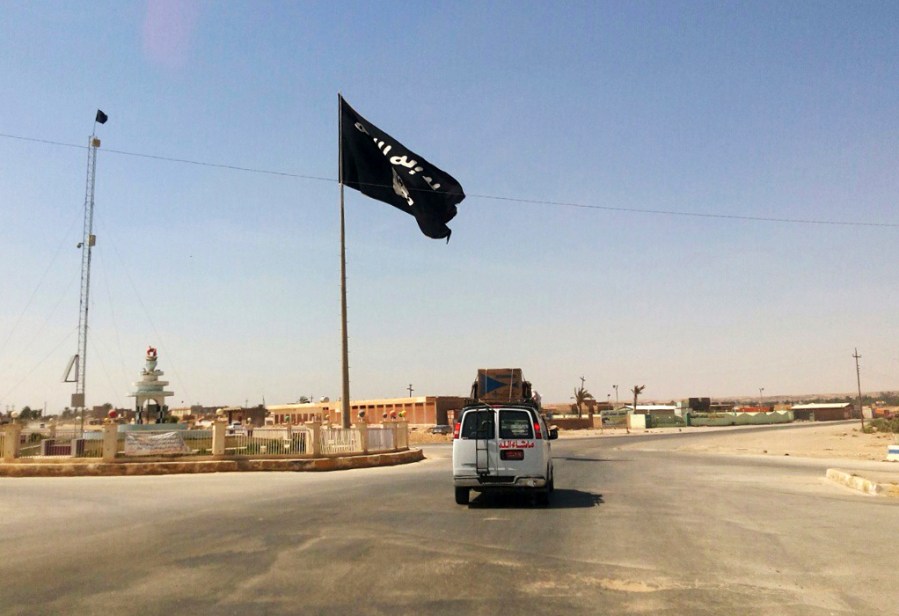 FILE - A vehicle passes by a flag of the Islamic State group in central Rawah, 175 miles (281 kilometers) northwest of Baghdad, Iraq. U.N. investigators are compiling evidence on the development and use of chemical weapons by Islamic State extremists in Iraq after they seized about a third of the country in 2014, and are advancing work on the militant group’s gender-based violence and crimes against children, Sunni and Shiite Muslims, Christians and Yazidis, the head of the investigative team said Wednesday, June 7, 2023. (AP Photo/File)