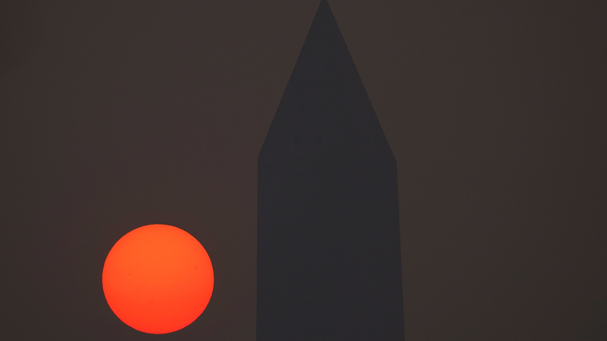 The sun rises behind the Washington Monument and a thick layer of smoke, Thursday, June 8, 2023, in Washington. Intense Canadian wildfires are blanketing the northeastern U.S. in a dystopian haze, turning the air acrid, the sky yellowish gray and prompting warnings for vulnerable populations to stay inside. (AP Photo/Julio Cortez)